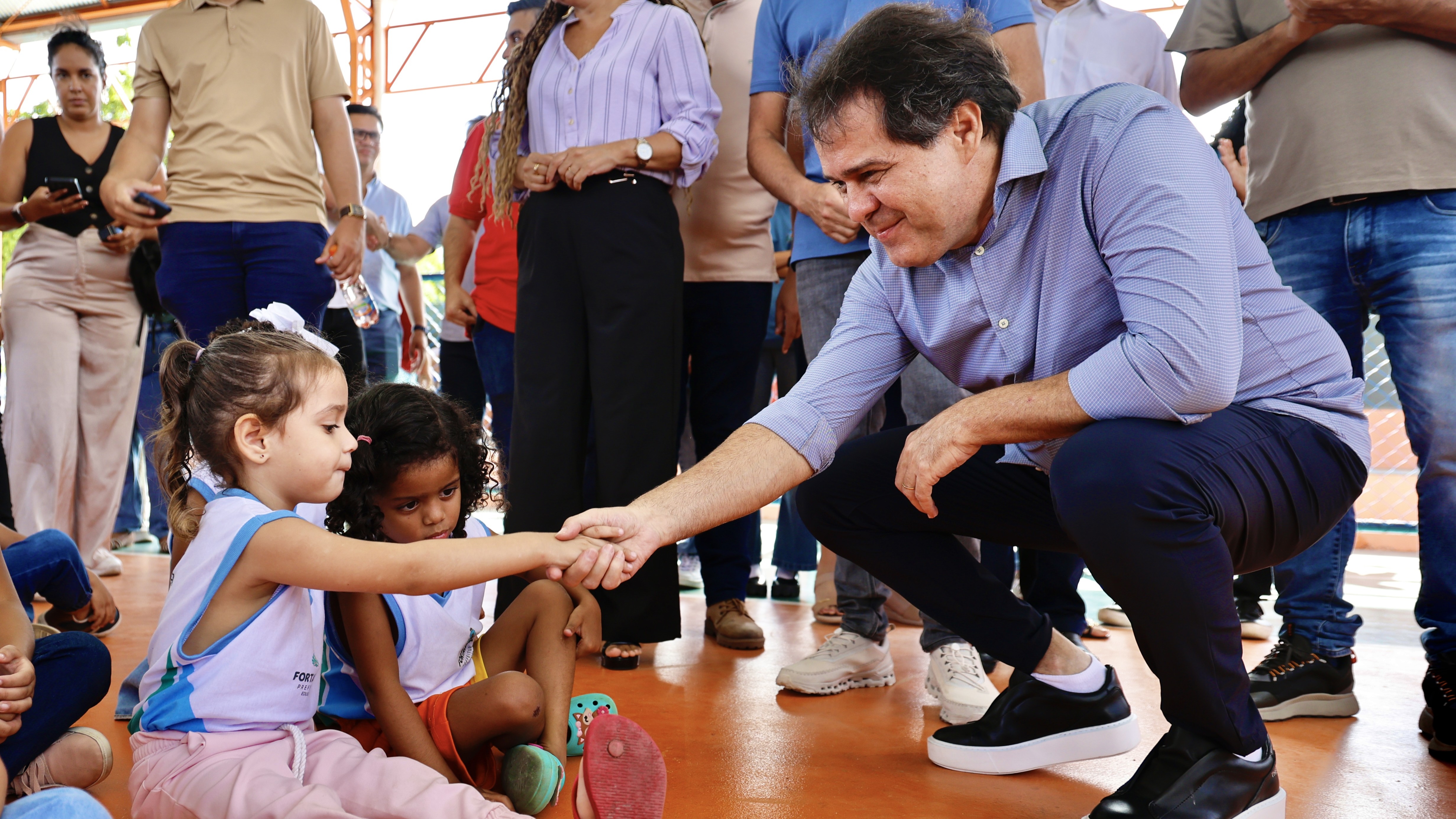 Prefeito Evandro falando com uma criança sentada num ginásio